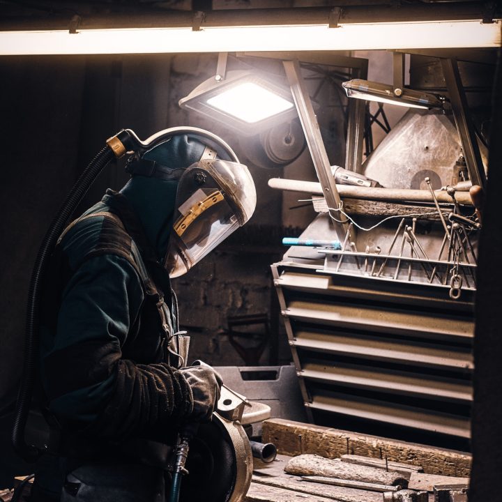 Experienced worker is repairing metal parts for machine tool at busy factory.